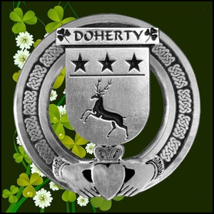 Könnte beinhalten: Ein silbernes keltisches Knotendesign mit einem silbernen Schild, der drei Sterne und einen springenden Hirsch zeigt. Der Schild ist von einem silbernen Ring mit dem Text "DOHERTY" und einem Kleeblatt auf jeder Seite umgeben. Das Design ist vor einem grünen Kleeblatthintergrund platziert.