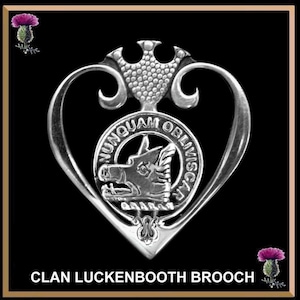 May include: Silver Clan Luckenbooth brooch with a heart-shaped design and a boar's head crest. The crest is surrounded by a circle with the inscription "NUNQUAM OBLIVISCAR".