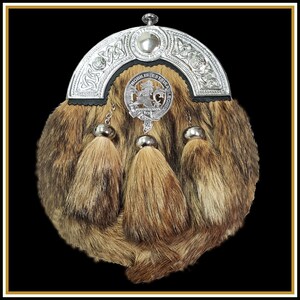 May include: A silver kilt pin with a lion crest and the text "Nobilis Est Ira Leonis" on a brown fur sporran with three tassels.
