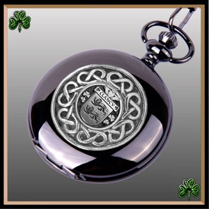 May include: Black pocket watch with a silver Celtic knot design and a silver crest featuring the name "Clancy" and a shamrock design.