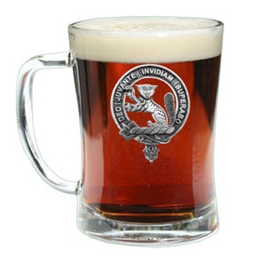 Könnte beinhalten: Ein klares Glasbierkrug mit einem Zinnwappen, das eine Katze und den Text "DEO JUVANTE INVIDIAM SUPERABO" zeigt.