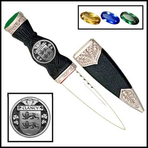 May include: A black and silver Celtic dagger with a green handle and a silver crest featuring the name "Clancy". The dagger is supplied with a black and silver scabbard.