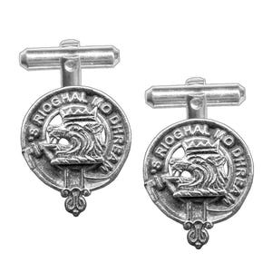 May include: A pair of silver cufflinks featuring a wolf's head crest with the text "S Rioghal Mo Dhirean".