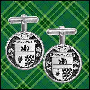 May include: A pair of silver cufflinks featuring a heraldic crest with the text "McAvoy" and a shamrock design.