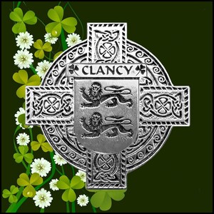 May include: A silver Celtic cross with a shield in the centre. The shield has two lions and the text "CLANCY" above them. The cross is surrounded by a circular design with Celtic knots.