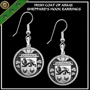 May include: Silver-toned Sheppard's Hook earrings with a circular pendant. The pendant features the text "KAVANAGH" above a coat of arms with a lion and shamrocks. The earrings are Irish themed.