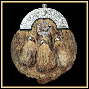 May include: A silver kilt pin with a black leather strap and three brown fur tassels. The pin features a Celtic knot design and a crest with a rooster and the text "Commit Thy Work To God".