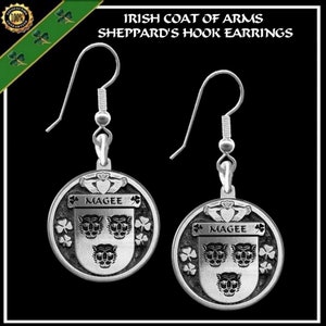 May include: Silver earrings featuring the Magee Irish coat of arms. The earrings are round and have a silver hook. The coat of arms features three lions' heads and a shamrock.