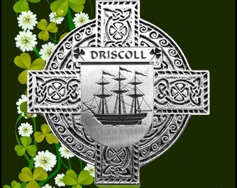 Könnte beinhalten: Ein silbernes keltisches Kreuz mit einem Schiffsdesign in der Mitte und dem Wort "DRISCOLL" über dem Schiff. Das Kreuz ist von einem dekorativen Rand aus keltischen Knoten und Kleeblättern umgeben. Der Hintergrund ist ein grünes Kleeblatt-Muster.