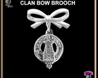 Op de afbeelding: Zilveren clan strik broche met een witte strik en een wapen met een toren met de tekst "IN ARDUA TENOT" eromheen.