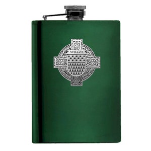 May include: A green stainless steel flask with a silver Celtic cross design featuring the word "WILCOX" on a shield.
