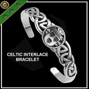 May include: Silver Celtic interlace bracelet with a round pendant featuring a crest with the name "Magee" and three shamrocks. The pendant also features three stylized animal heads.