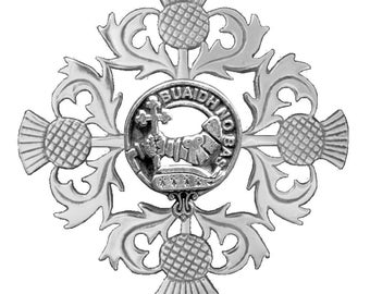 May include: A silver-toned brooch featuring a central circular emblem with the text "BUAIDH NO BAS" and a detailed design. The brooch is adorned with four thistles and ornate, swirling leaves.