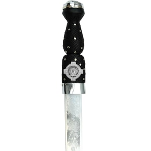 May include: A Scottish dirk with a black handle adorned with silver studs and a decorative silver emblem. The blade is silver with an etched floral design. The dirk is a traditional Scottish knife.