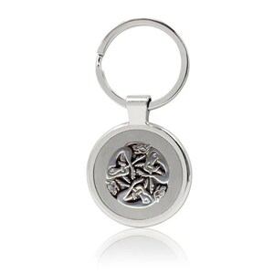 May include: A silver-colored keychain with a circular pendant. The pendant features a detailed, raised Celtic knot design in the center. The keychain includes a split ring for attaching keys.