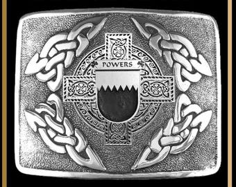 May include: A rectangular silver-toned kilt buckle featuring an intricate Celtic cross design with interlaced knotwork patterns in the corners. The center displays a shield with the text POWERS engraved on a horizontal band above a jagged line.