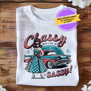 May include: A white t-shirt with a graphic design of a woman in a polka dot dress standing next to a vintage car. The text "Classy with a side of Sassy!" is printed on the shirt.