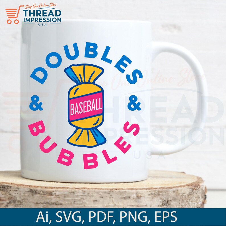 Op de afbeelding: Witte keramische mok met de woorden "DOUBLES & BUBBLES" in blauw en roze, rond een snoepvormige honkbalafbeelding. De mok heeft ook de tekst "BASEBALL" in een roze rechthoek. De mok staat op een houten oppervlak.