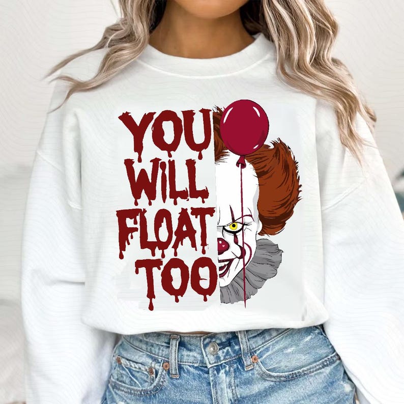 May include: White sweatshirt with a red graphic of a clown with a red balloon and the text "YOU WILL FLOAT TOO".