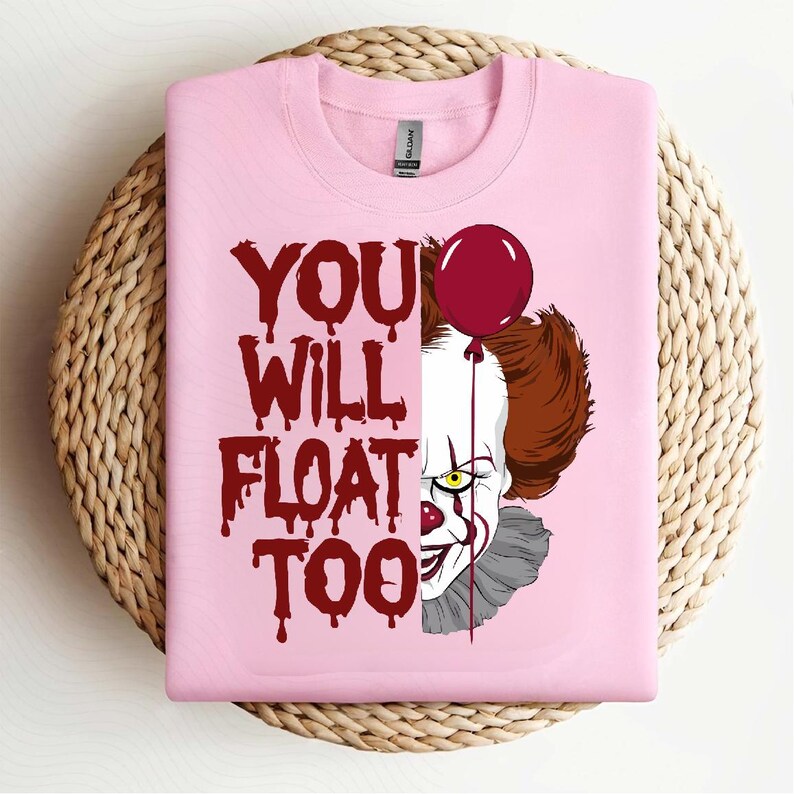 May include: Pink t-shirt with a red and white graphic of Pennywise the clown from the movie "IT" with the text "You Will Float Too".