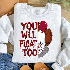 May include: A gray sweatshirt with a red and white graphic of Pennywise the clown from the movie "It". The graphic includes the text "You Will Float Too" and a red balloon.