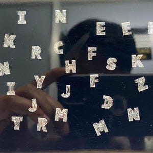 Pode incluir: Uma coleção de adesivos de letras prateadas em um fundo preto. As letras incluem F, L, I, N, E, R, B, W, K, C, H, S, Z, Y, J, D, M, O, T e K.