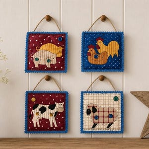 May include: Four square fabric wall hangings featuring farm animal appliques. The top left shows a pig, top right shows two chickens, bottom left shows a cow, and bottom right shows a sheep. Each piece has a jute twine hanger and blue trim.
