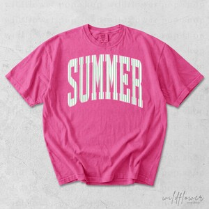May include: A hot pink t-shirt with the word "SUMMER" printed across the front in large, white, vertical striped letters. The shirt has short sleeves and a crew neck.