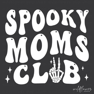 May include: A dark gray graphic design featuring the white text SPOOKY MOMS CLUB in a wavy, retro font. The letter U in CLUB is replaced by a white skeleton hand making a peace sign. Four small white four-pointed stars accent the design.