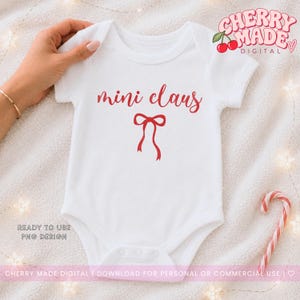 Op de afbeelding: Een wit babyrompertje met korte mouwen voorzien van de rode tekst mini claus en een rode strik-afbeelding in het midden op de borst. Het ontwerp wordt gepresenteerd als digitaal bestand om te downloaden, met de tekst Cherry Made Digital en een kersenicoon.