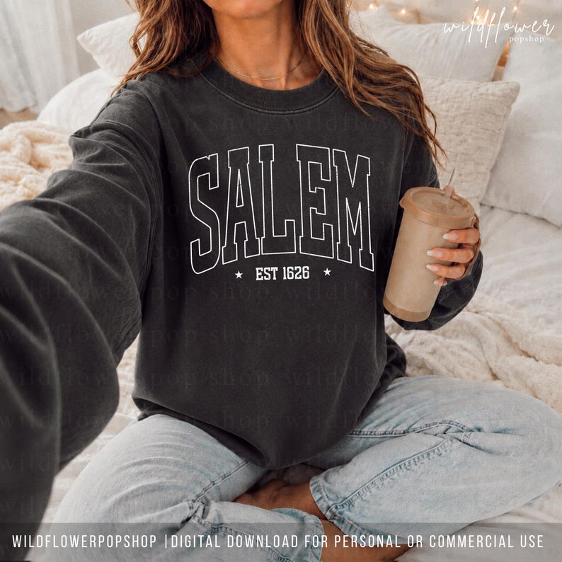 May include: A charcoal gray crewneck sweatshirt featuring the white text SALEM in a bold collegiate font, with the text EST 1626 and two small stars centered below. The garment has long sleeves and a ribbed neckline, cuffs, and hem.