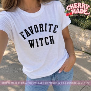 Może przedstawiać: Biały t-shirt z krótkim rękawem z czarnym, postarzanym napisem FAVORITE WITCH wydrukowanym pogrubioną, łukowatą czcionką na klatce piersiowej. Projekt zawiera małe logo w prawym górnym rogu z napisem CHERRY MADE DIGITAL.