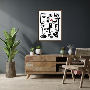 May include: A black and white abstract art print with a brown frame, hanging on a dark gray wall above a wooden console table with a potted plant and a chair.