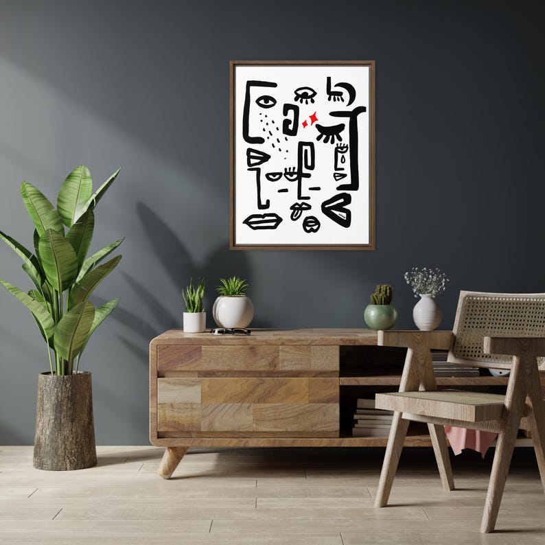 May include: A black and white abstract art print with a brown frame, hanging on a dark gray wall above a wooden console table with a potted plant and a chair.