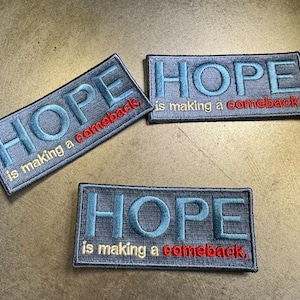 May include: Three gray fabric patches with the word "HOPE" embroidered in blue and the text "is making a comeback." in white and red.