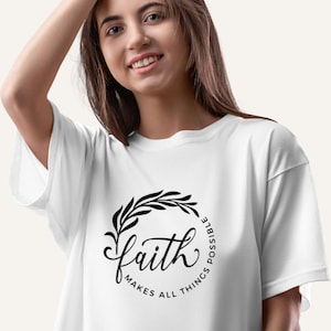 Puede incluir: Camiseta blanca con un diseño gráfico negro que dice "faith makes all things possible" con un diseño floral alrededor del texto.