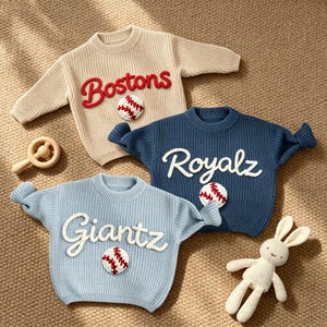 May include: Three long-sleeve knit jumpers in beige, dark blue, and light blue. The beige jumper features red text reading Bostons, the dark blue features white text reading Royalz, and the light blue features white text reading Giantz.