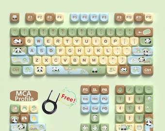 Könnte beinhalten: Ein Satz Panda-Keycaps für eine mechanische Tastatur. Die Keycaps sind in verschiedenen Farben, darunter Grün, Braun, Gelb und Weiß. Die Keycaps zeigen Pandabären, Bambus und andere von der Natur inspirierte Designs. Die Keycaps sind mit den Buchstaben des Alphabets, Zahlen und Symbolen beschriftet. Die Keycaps sind für Tastaturen mit 61, 64, 68, 75, 82, 84, 87, 96, 98, 100, 104 und 108 Tasten ausgelegt. Die Keycaps sind aus PBT-Kunststoff gefertigt und haben ein "MCA-Profil".