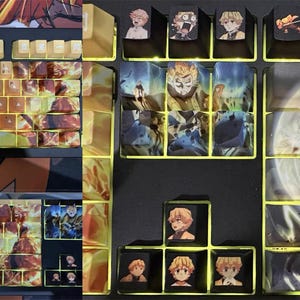 May include: A keyboard with custom keycaps featuring anime characters. The keycaps are arranged in a grid pattern and have a variety of colours and designs. The keyboard is black and has a silver frame.