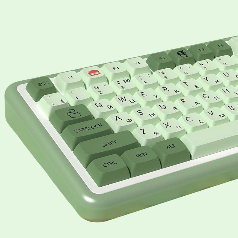 May include: A green and white keyboard with various keys labeled with letters, numbers, and symbols. Some keys have icons on them, including a hamburger, a cupcake, and a cup of coffee.