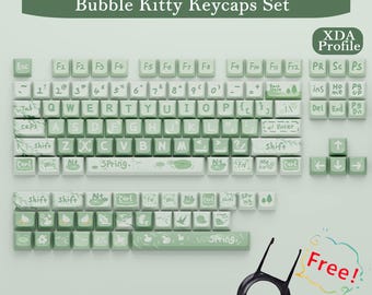 Puede incluir: Un juego de teclas Bubble Kitty en verde claro y blanco. Las teclas presentan un patrón similar al mármol e iconos decorativos. El juego incluye un extractor de teclas y el texto "Free!"