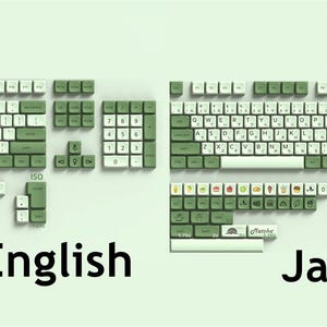 May include: A green and white keyboard with two different layouts: English and Japanese. The English layout has a standard QWERTY keyboard with green keycaps and white lettering. The Japanese layout has a similar design with green keycaps and white lettering, but with additional keys for Japanese characters.