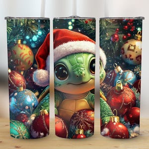 May include: A set of three stainless steel tumblers featuring a cartoon turtle wearing a Santa hat, surrounded by Christmas ornaments. The tumblers have a festive holiday theme with a green, red, and gold color scheme.