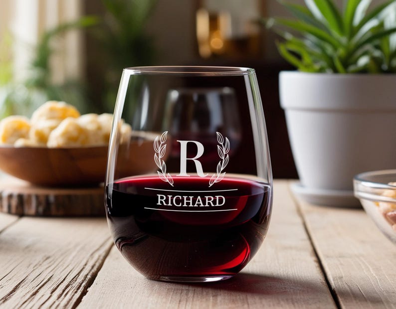 Peut inclure: Un verre &agrave; vin sans pied avec un design personnalis&eacute;. Le verre est rempli de vin rouge et pr&eacute;sente une initiale "R" grav&eacute;e en blanc avec une couronne de laurier et le nom "RICHARD" en dessous.