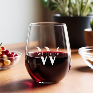 Peut inclure: Un verre &agrave; vin en verre transparent avec un pied, rempli de vin rouge. Le verre porte le nom "Whitney" et les lettres "WW" grav&eacute;es sur le c&ocirc;t&eacute;.