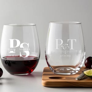 Peut inclure: Deux verres &agrave; vin en verre transparent avec des gravures personnalis&eacute;es. Le premier verre porte les initiales "P&S" avec les noms "Paris" et "Samuel" et la date "12.12.21". Le deuxi&egrave;me verre porte les initiales "P&T" avec un motif de c&oelig;ur et de spirale et la date "Jan. 10, 2022".