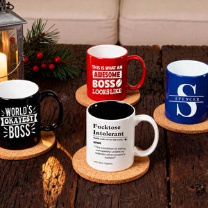 Pu&ograve; includere: Quattro tazze in ceramica con testi e disegni umoristici su sottobicchieri in sughero. Le tazze sono nere, rosse, bianche e blu. La tazza nera dice "World's Okayest Boss". La tazza rossa dice "This is what an Awesome Boss Looks Like."