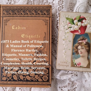 May include: A tan hardcover book titled Ladies' Etiquette & Manual of Politeness by Florence Hartley, featuring black decorative borders. Beside it is a rectangular card titled Love's Message, showing a portrait of a person and lily of the valley.