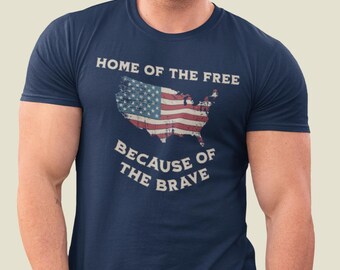 Può includere: T-shirt blu navy con un designo di bandiera americana usurato e il testo "Home of the Free Because of the Brave".