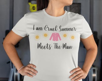 May include: White t-shirt with the text "I am Cruel Summer Meets The Man" in black script. The design includes yellow suns and a pink blazer graphic. The shirt is short-sleeved.